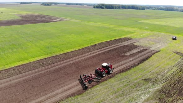 Red Harvester Drives Across Field and Plows Earth