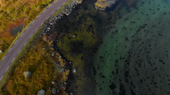 Drone flying next to the street, and car is passing. Next to the shore in Norway