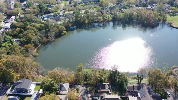 An aerial view over Grant Pond in a Long Island, NY suburb. The camera truck right, tilted down over
