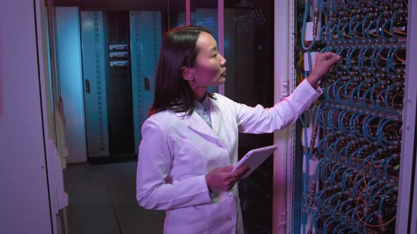 Female IT Specialist with Tablet Checking Equipment in Data Center