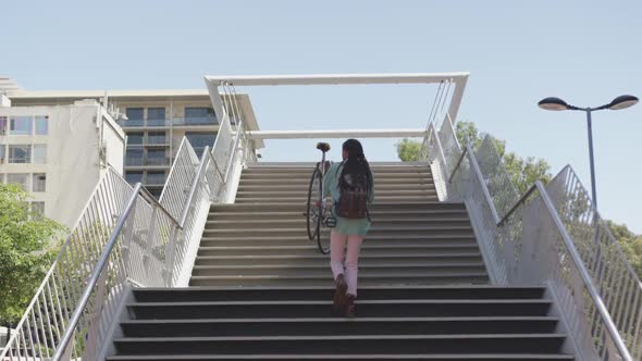 Mixed race man climbing stairs with a bike