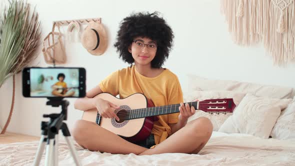 Afro American Woman Blogger Playing Guitar While Sitting on Bed at Home