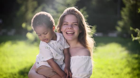 Happy Lightskinned European Woman Holds African Baby Girl in Her Arms