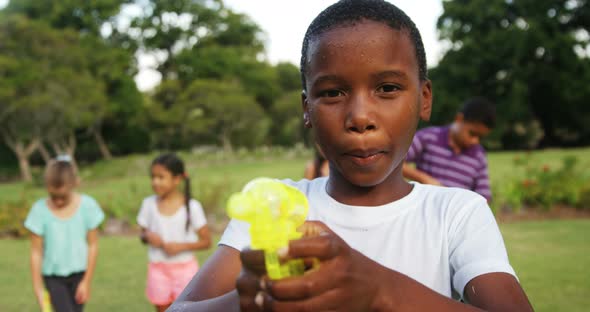 Portrait of smiling boy playing with water gun alt