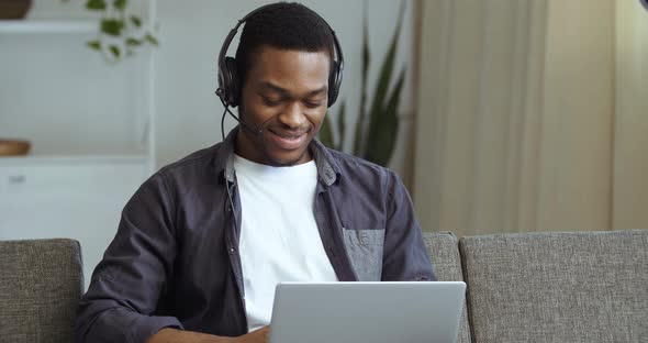 Afro American Man Wears Head Microphone and Headphones Speaks on Webcam Answers Video Call