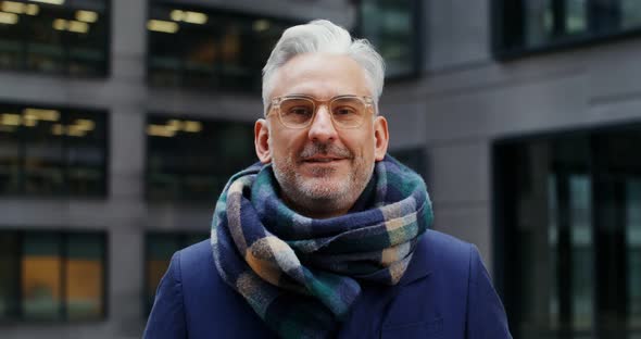 A Grayhaired Man Smiles Looking at the Camera While Standing in Business Center