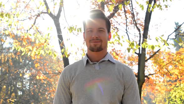 Handsome Young Happy Guy Stands in the Forest Who Has Sunshine Behind His Head