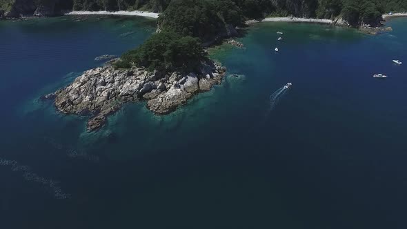 Aerial Over Small Island Covered with Tropical Rainforest Stone Shore Belt Around Woods