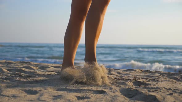 Female Feet Walking Barefoot on Seashore During Sunny Day. Legs of Young Woman Stepping at Sand