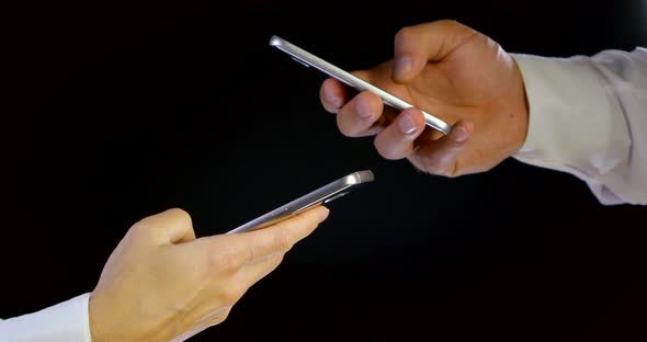 Close-up of Male and Female Hands Typing Touch Screen Mobile Phone Smart Device on Black Isolated