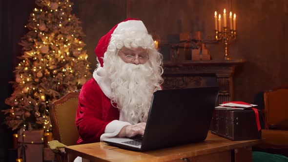 Workplace of Santa Claus. Cheerful Santa is working while sitting at the table.