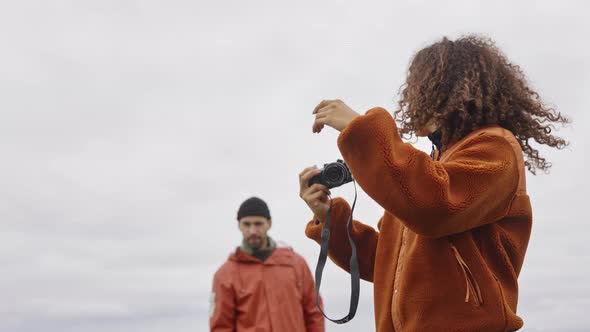 Young Female Hiker Pointing To Partner Under Cloudy Sky