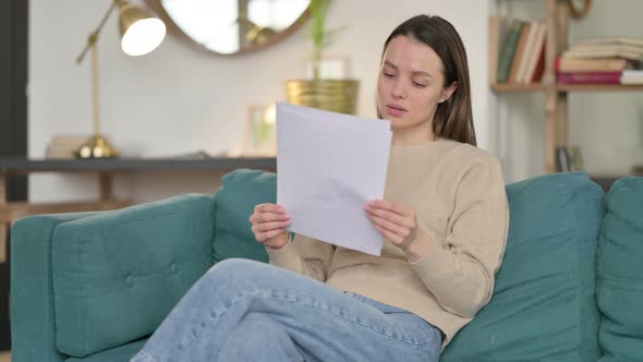 Young Woman Reading Documents on Sofa 