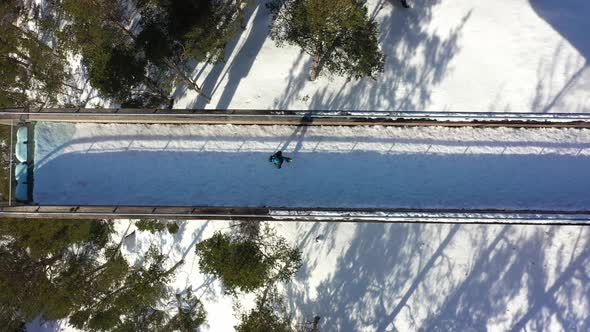 Man walking towards edge of Stegastein viewpoint seen from birdseye perspective - Cool top-down view