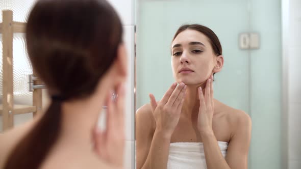 Skin Care. Woman Touching Face And Looking At Mirror At Bathroom