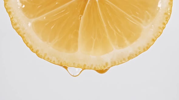 Slow Motion of Flowing the Juice From Lemon Slice on White Background