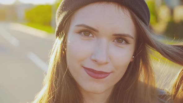 Portrait of a hipster and trendy young girl in a hat posing at sunset