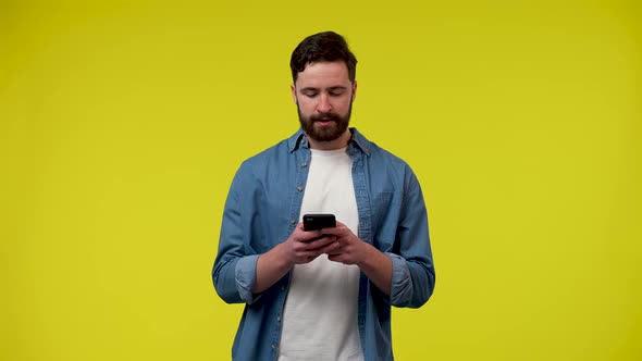 Portrait of a Handsome Caucasian Man Writing a Text Message on His Mobile Phone and Madly Rejoicing