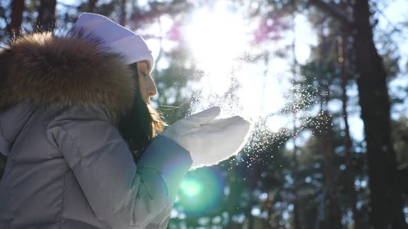 Profile of Pretty Woman in White Gloves Blowing Off Snow From Her Palms