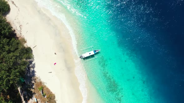 Aerial drone shot landscape of luxury coastline beach break by blue green water with white sand back