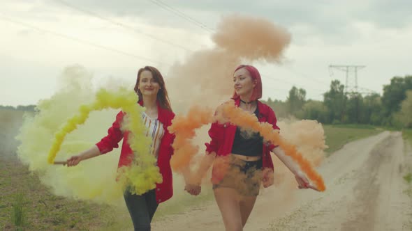 Two Bright Females Walking in Color Smoke on Road