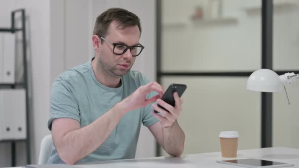 Attractive Young Man Using Smartphone at Work