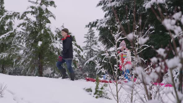 Kids walking through snow with sleds in winter