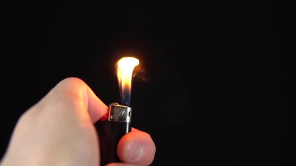 A Man Lights a Lighter. A Man Holds a Lighter in His Hand and Spins a Drum on a Black Background