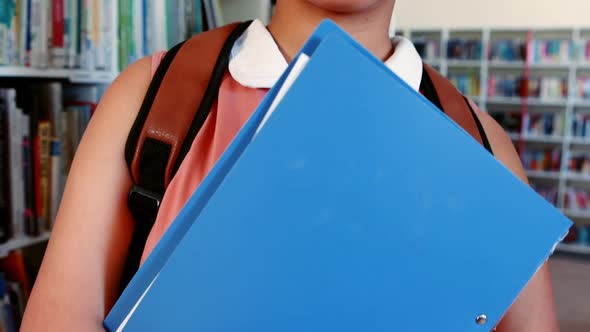 Portrait of happy schoolgirl standing in library