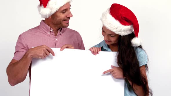 Casual festive couple pointing to card