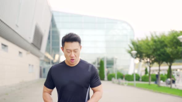 young asian man runner running down the street on urban background of city and park 