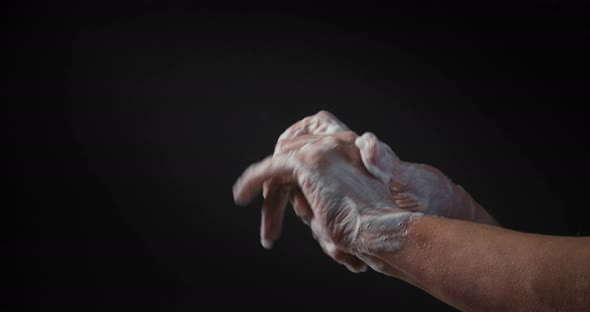 Close Up of Female Lathering Hands with Soap Before Washing on Black Background