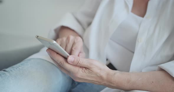 Close Up of Elderly Woman Spends Her Time at Home Using Her Cell Phone and Having Pleasur