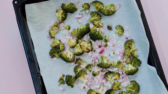 Baked broccoli with onions on baking paper on a baking sheet