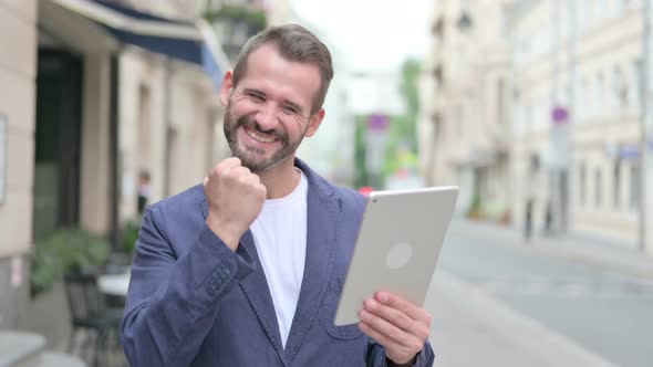 Mature Adult Man Celebrating on Tablet Outdoor