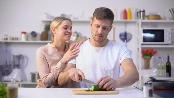 Husband Slicing Vegetable, Loving Wife Embracing Him, Romantic Moment in Kitchen