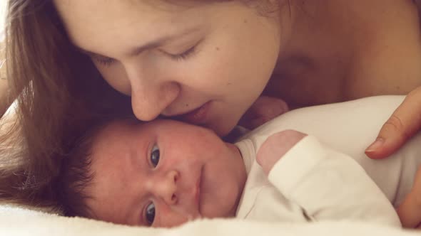 Newborn baby boy and his mother at home. Close-up portrait of the infant