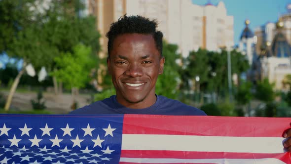 Close Up Smiling Patriot AfroAmerican Man Holding American Flag Looks Camera