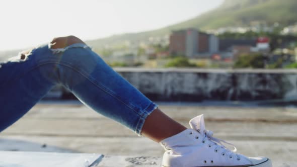 Fashionable young woman on urban rooftop using smartphone