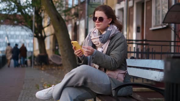 Traveller European Woman Have a Chat in Smartphone Sitting on the Bench in the Street of Old Town