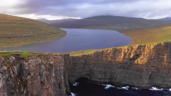 Aerial View of Cliff Covered in Grass Blue Sea Sun Clouds