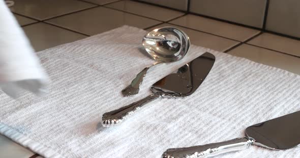 A woman drying off a set of vintage silverware after cleaning and polishing it to re tarnish and mak