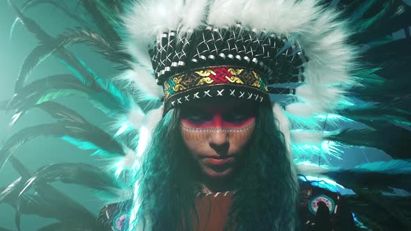 Beautiful Girl in Native American Indian Headdress and Costume with Colorful Makeup Makes Movements