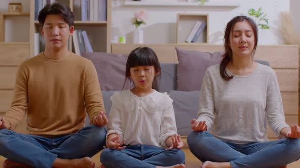 Calm asian family doing yoga meditation concentrate of deep breath at home.Peaceful young parent exe