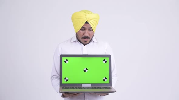 Happy Bearded Indian Sikh Businessman Looking Surprised While Showing Laptop