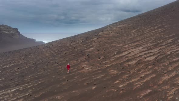 Tourist in Red Sweatshirt Walks Across the Volcanic Hill