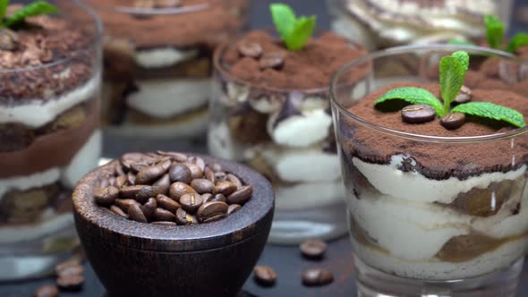 Group of Portions of Classic Tiramisu Dessert in a Glass Cup on Stone Board on Concrete Background