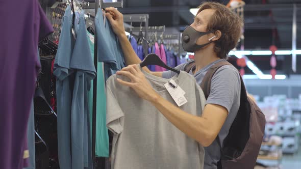 A Man in a Clothing Store in a Medical Mask Because of a Coronovirus