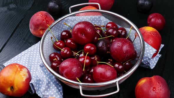 Nectarine and a Handful of Sweet Cherries Lie on a Black Wood Background