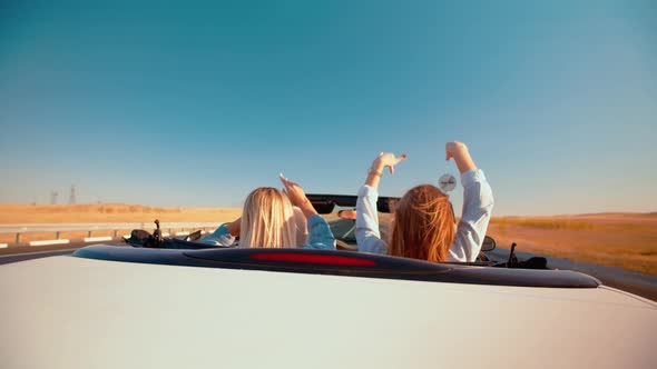 White Convertible with Two Women Driving Ahead on Highway Rear View